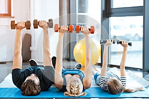 Family exercising with dumbbells at fitness studio