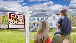 Family Facing Sold For Sale Real Estate Sign and House