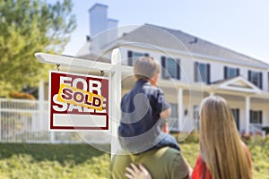 Family Facing Sold For Sale Real Estate Sign and House