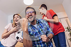 Family of fans watching a football match on TV