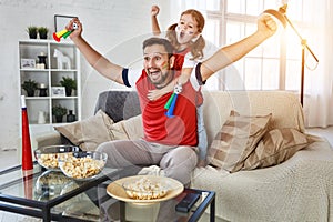 Family of fans watching a football match on TV at home