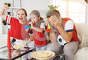 Family of fans watching a football match on TV at home