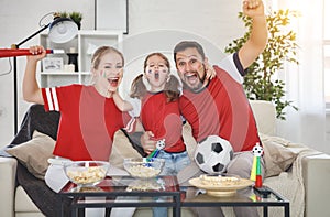 Family of fans watching a football match on TV at home