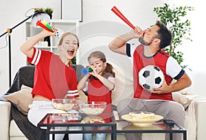 Family of fans watching a football match on TV at home