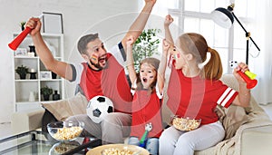 Family of fans watching a football match on TV at home