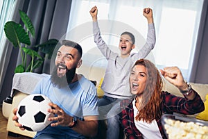 Family of fans watching a football match on TV at home