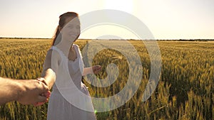 Family of farmers. a girl and man walk on field of wheat, holding hands in rays of summer sun. girl and guy travel out