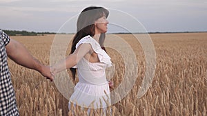Family of farmers walks through wheat field holding hands. beautiful girl farmer holds in his arms his boyfriend. Follow