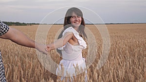 Family of farmers walks through wheat field holding hands. beautiful girl farmer holds in his arms his boyfriend. Follow