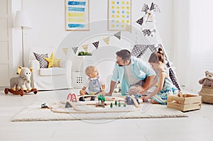 Family father and children play a toy railway in playroom