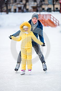 Family of father and kid having fun on skating rink outdoors