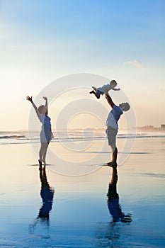 Family - father, mother, baby walk on sunset beach