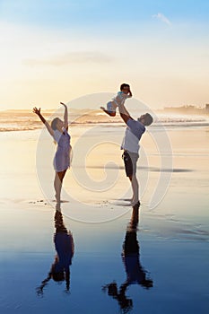 Family - father, mother, baby walk on sunset beach