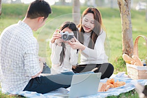 Family father, mother and child having fun and enjoying outdoor together sitting on the grass party with shooting photos