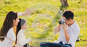 Family father, mother and child having fun and enjoying outdoor together sitting on the grass party with shooting photos