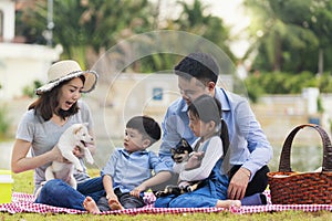 A family with a father, mother and daughter, son on a picnic And play with Shiba Inu puppies