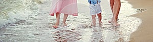 Family Father mother and little son walk barefoot along the seashore