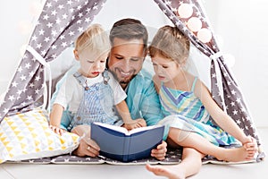 Family father reading to children book in tent at home