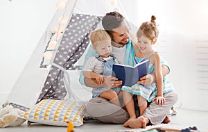 Family father reading to children book in tent at home
