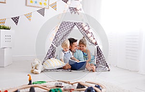 Family father reading to children book in tent at home