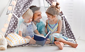 Family father reading to children book in tent at home