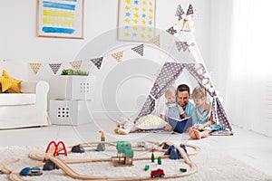 Family father reading to children book in tent at home