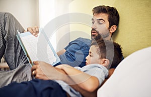 Family, father and son with a book, home or reading with bonding, development and relax in a bedroom. Happy parent, male