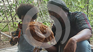 Family with father and son carrying hen in the farm, dad and children holding chicken for agriculture.