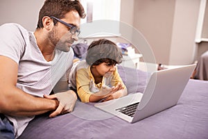 Family, father and son with laptop in bed for cartoon, movie and connectivity with technology for online streaming