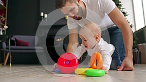 Family, fatherhood and people concept - happy father with little baby son playing with toys at home