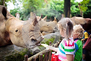 Kids feed rhino in zoo. Family at animal park photo