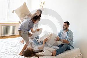 Family fighting with pillows spend funny time in bedroom