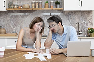 Family financial crisis concept. Shocked and stressed couple counting expenses, taxes and debts