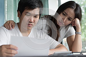 Family financial crisis. Stressed asian couple looking at issues notification from bank about late payment home loan credit