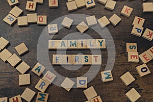 Family first. Strong message created by colorful wooden puzzles on a dark wooden background. Family concept