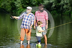 Family fishermen fishing with spinning reel. Boy with father and grandfather fly fishing outdoor over river background.