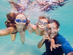 Family fitness - mother, father, baby son learn to swim together, dive underwater with fun in pool Active parent lifestyle, people