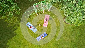 Family fitness and sport outdoors, group of active girls doing workout in park, aerial top view