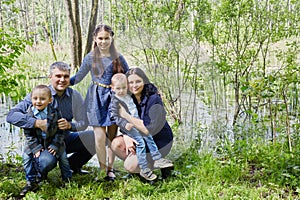 Family of five poses on boggy pond shore in summer photo