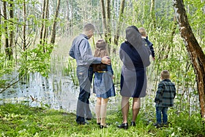 Family of five stands on boggy pond shore in photo