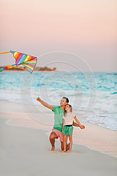 Family flying kite together at tropical white beach
