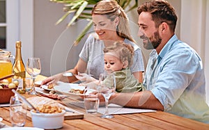 Family, food and lunch outdoor with child, mom and dad together for meal, wine and bonding at patio dining table. Baby