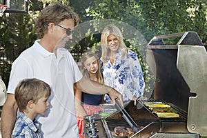 Family of four barbecuing