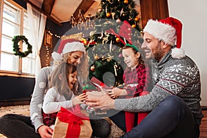 Family of four celebrating Christmas, exchanging presents