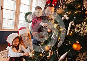 Family of four decorating a Christmas tree photo