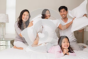 Family of four having pillow fight on bed