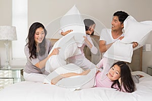 Family of four having pillow fight on bed