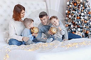 A family of four hugging in front of the christmas tree. love, happiness and big family concept