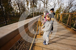 Family with four kids looking at wild animals from wooden bridge