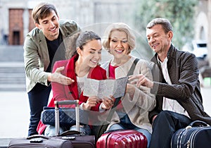 Family of four with luggage checking direction in map